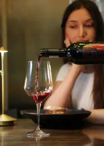 Common Wine Mistakes 1 Hand opening a champagne bottle incorrectly with cork popping out forcefully, highlighting common sparkling wine mistakes.