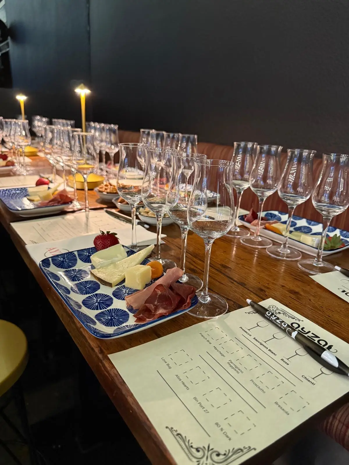 Image displays a selection of fine wines alongside a curated cheese board with brie, gouda, and blue cheese, designed for a corporate networking event. Guests are seen chatting in the background.
ALT: Wine and cheese tasting table at AYZA, designed for business networking events.